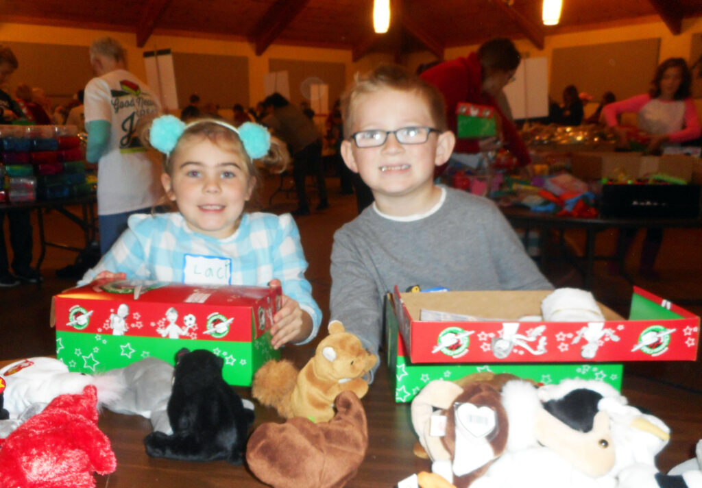 JEAN SEEGERS, PHOTO - The Herald. Cousins Drew Pettit and Lucy Brewer-Olmstead helped pack shoeboxes for the Operation Christmas Child Project at Hope Church, Saturday, Nov. 12. The boxes will be sent to needy children in third world countries. 