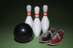 Bowling ball, bowling shoes and bowling pins side by side