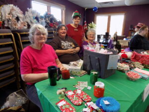 MARGARET DOWNING, PHOTO - The Journal. Diane Benjamin, of Loves Park, left; along with her sister to help out, had some nice holiday decorations and baked goods to offer at the Park Towers craft and bake sale Dec. 9. 