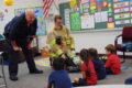 ANNE EICKSTADT PHOTO Belvidere Republican
	Firefighter Jeff describes what each part of the firefighting gear is for as Firefighter Glenn stays low to avoid intimidating the preschoolers in the class at St. James.